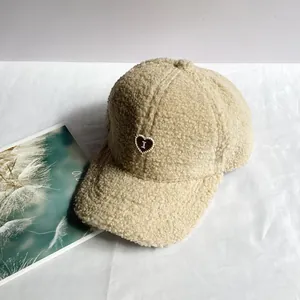 Dettaglio del berretto beige in lana d'agnello con ricamo a cuore rosso e trama soffice