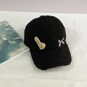 Gros plan sur la casquette en sherpa noir avec patch lapin et nœud en vichy élégant