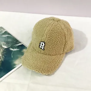 Detailed view of R letter embroidery on warm khaki sherpa fleece baseball cap