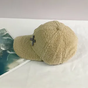 Détail d'une casquette en polaire teddy beige avec un petit nœud à carreaux sur le côté