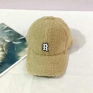 Detailed close-up of beige sherpa baseball cap with 3D embroidered letter R logo