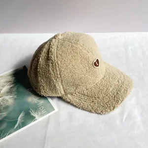 Dettaglio del berretto beige in lana di agnello con toppa ricamata a forma di cuore