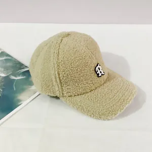 Detailed close-up of a warm beige lamb wool baseball cap with an embroidered R patch