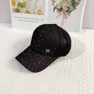 Detail of black sequin baseball cap showing breathable mesh and circular metal MC logo