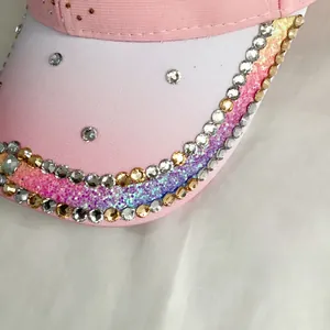 Detail of pink baseball cap brim featuring gradient glitter and rhinestone heart accents