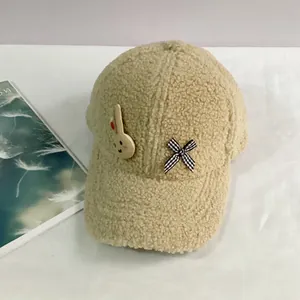 Détail de la casquette en laine d'agneau avec écusson lapin et nœud papillon à carreaux
