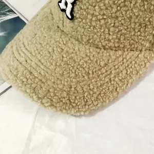 Close-up of the khaki lamb wool texture and embroidered logo on the warm baseball cap