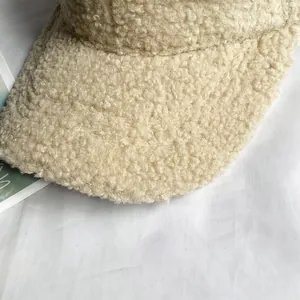 Dettaglio del cappellino beige in lana d'agnello con trama bouclé spessa e tessuto morbido