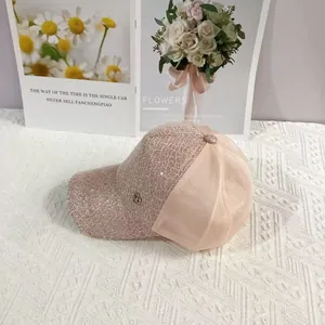 Detail of pink lace baseball cap with sequins and a small circular metal logo tag