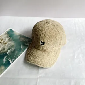 Detail der khakifarbenen Fleece-Baseballkappe mit Teddybär-M-Patch und Perlenakzenten