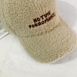 Close-up detail of NO TIME FOR ROMANCE embroidery on beige teddy fleece baseball cap
