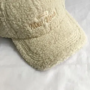 Close-up of beige fuzzy sherpa baseball cap featuring New York embroidery detail
