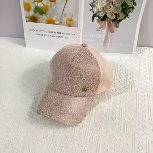 Close-up of lace baseball cap with MC metal logo and sparkling sequin details