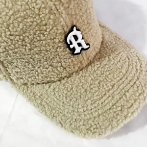 Detailed view of thick sherpa fleece texture and R-letter embroidery on the warm baseball cap