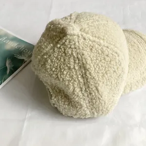 Close-up of beige faux shearling baseball cap with dandelion embroidery on white paper