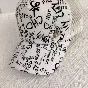 Close-up of glitter fabric with graffiti lettering and silver M logo on a baseball cap
