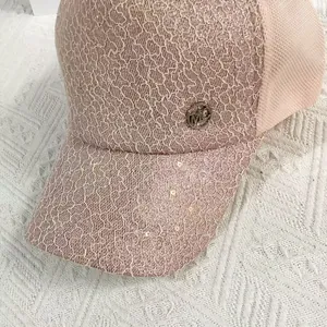 Detail view of pink lace baseball cap with metal MC logo and shimmering sequins