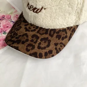 Close-up of plush cream baseball cap with leopard print brim and embroidered new lettering