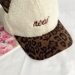 Detail of plush baseball cap with cream faux shearling and leopard print brim featuring embroidery