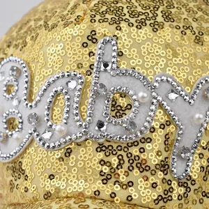 Close-up of golden sequin baseball cap with rhinestone and pearl baby lettering detail