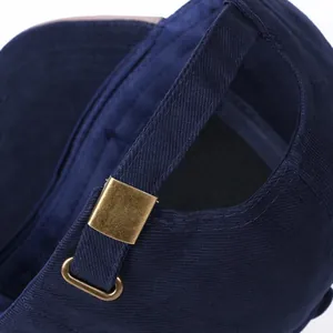 Adjustable back strap with bronze metal buckle on a navy blue cotton golf cap