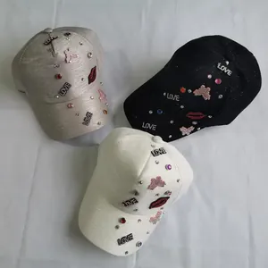 Detail view of rhinestone LOVE and red lip embroidery on baseball caps in three colors