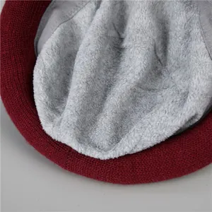 Detail of burgundy knit winter hat featuring thick warm grey fleece lining texture