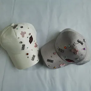 Detail of baseball caps with rhinestones, love letters and red lip patches