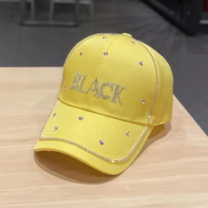 Dettaglio del cappellino da baseball giallo con scritte BLACK in strass e borchie lucide
