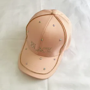 Dettaglio dei brillantini sulla corona del cappellino di cotone rosa pesca con scritta BLACK