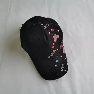 Detail of black baseball cap with sequin LOVE letters, rhinestone lips, and butterfly patch