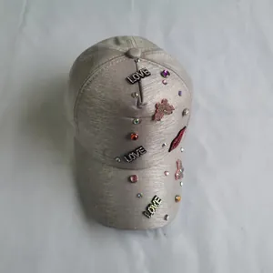 Detailed view of grey baseball cap featuring pink butterfly patches and red crystal lips