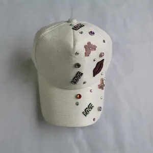 Detail view of white glitter baseball cap with rhinestone LOVE and red lip patch decorations