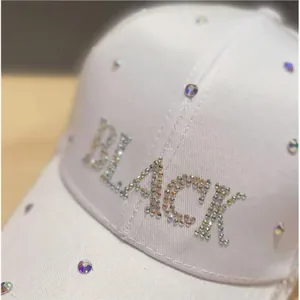 Dettaglio ravvicinato di strass colorati con scritta BLACK su un berretto bianco