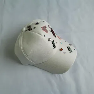 Close-up of sequin LOVE patches and rhinestone heart lip accents on a white baseball cap