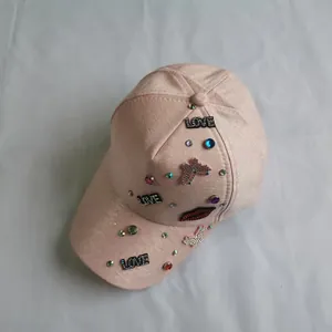 Detailed view of pink baseball cap with rhinestone LOVE patches and red lips embroidery