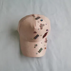 Close-up of pink baseball cap featuring rhinestone LOVE patches and red lip embroidery
