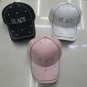 Dettaglio di berretti da baseball neri, bianchi e rosa con decorazioni in strass scintillanti