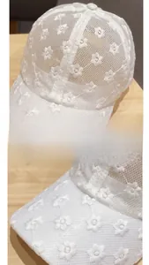 Detail of white lace baseball cap with floral embroidery and breathable mesh texture
