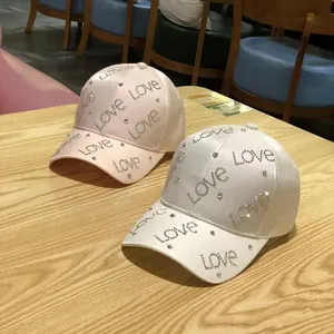 Women's stylish baseball caps in white and pink with rhinestone Love lettering and studs