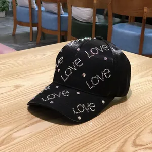 Detailed view of black baseball cap featuring sparkling rhinestone 'Love' lettering on wood