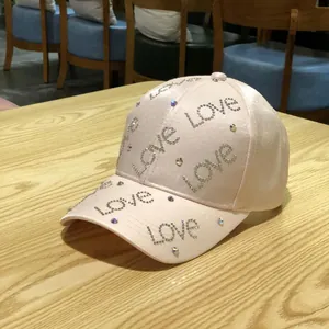 Detailed view of pink satin baseball cap with sparkling rhinestone Love lettering