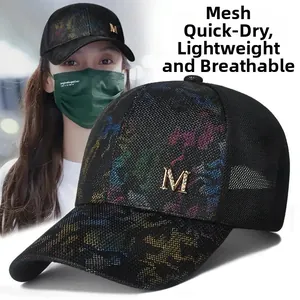 Close-up of black mesh baseball cap featuring a golden M logo and colorful paint splatter