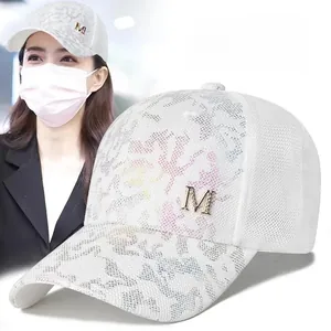 Detail of white mesh baseball cap featuring gold M logo and colorful camo pattern