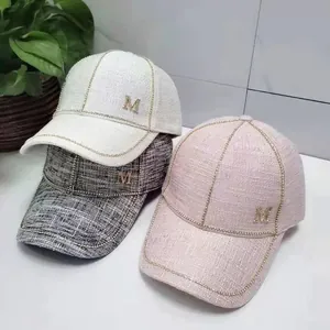 Detail of tweed baseball caps with rhinestone M logo in white, grey, and pink styles