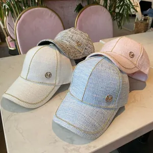 Detailed close-up of tweed baseball caps with gold M logo and chain trim in four colors