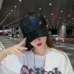 Close-up of black baseball cap with golden M logo and vibrant tie-dye pattern detail