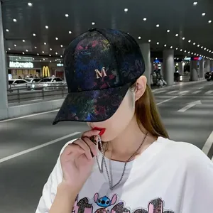 Detail of a baseball cap featuring a golden M logo with colorful rhinestone embellishments