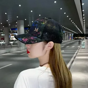 Detail of a mesh baseball cap featuring rainbow sequins and a golden metal M emblem