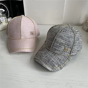 Close-up of tweed baseball caps with gold M logo, chain trim, and luxury texture